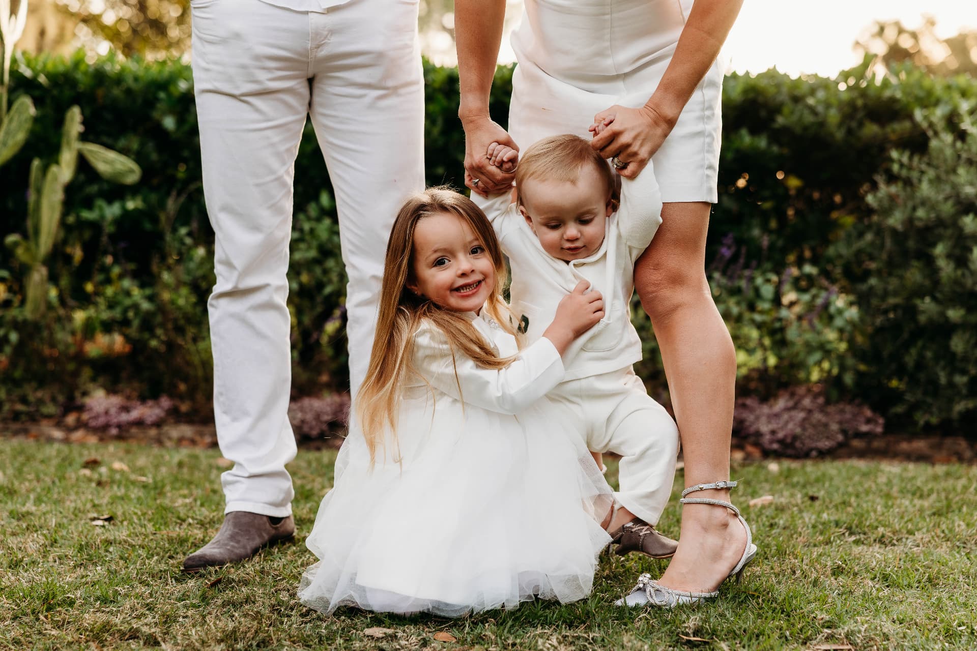 Brittany George's children — her daughter Haisley hugging her son Brody — with their parents in a garden at sunset